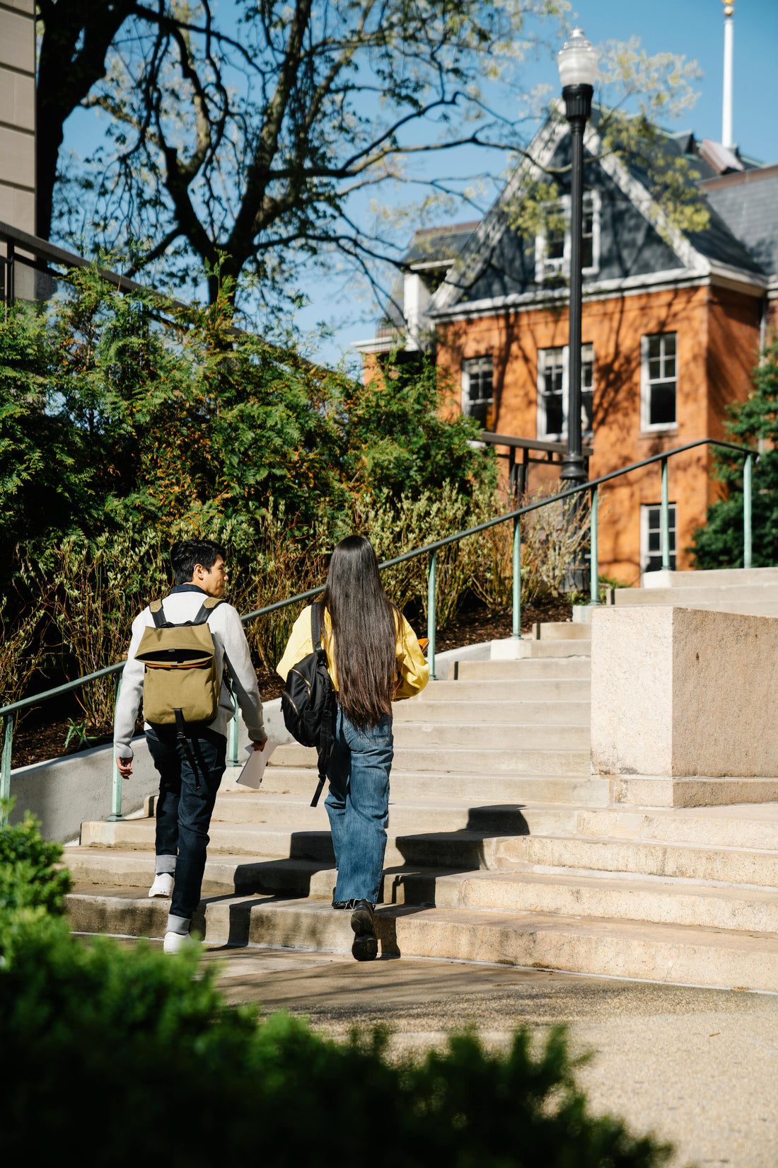Twee studenten lopen samen een trap op richting een campusgebouw, als symbool voor studeren in het buitenland.